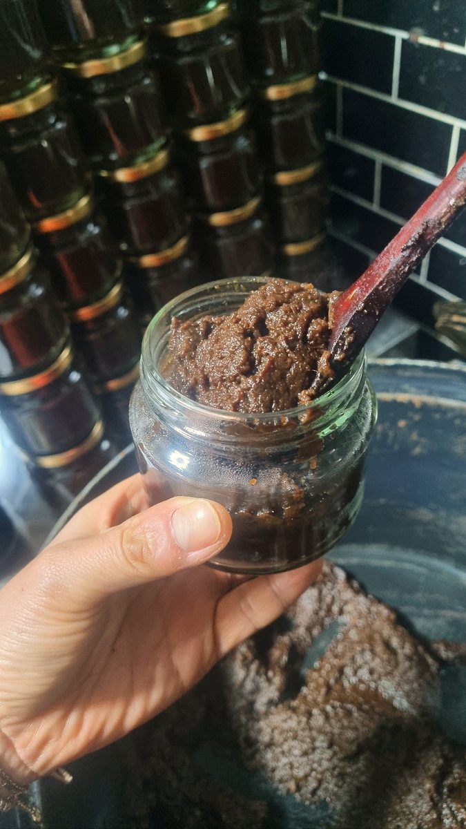 갓 채운 도라지청 병을 손으로 들고 있고 뒤로 병들이 줄지어 쌓인 작업 모습